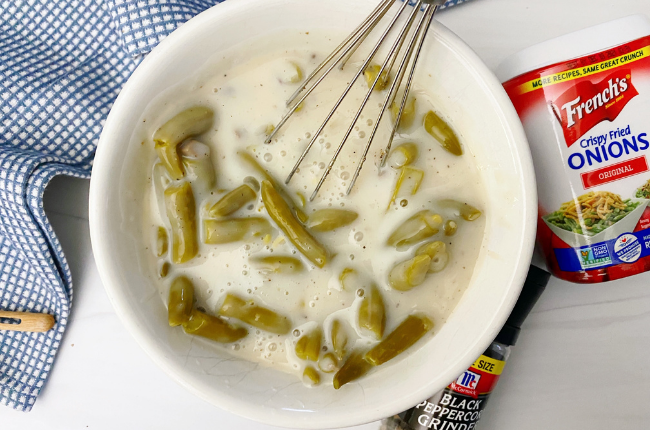 Mix the cream of mushroom soup, milk, green beans, and pepper together in a large bowl.