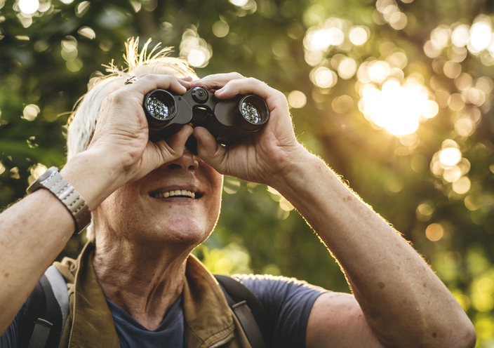 A man looks for birds through his binoculars on Audubon Day